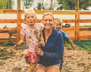 Group enjoying outdoor activities in a mud-filled enclosure with wooden fencing.