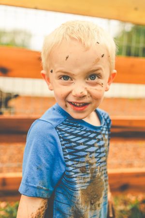 Close-up sequence showing a happy child in a blue t-shirt with mud splattered across their face.