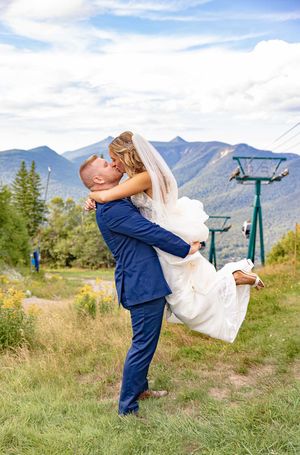Groom lifting bride for a kiss on the Loon mountain ski slopes in Lincoln NH on their wedding day in the White Mountians of New Hampshire