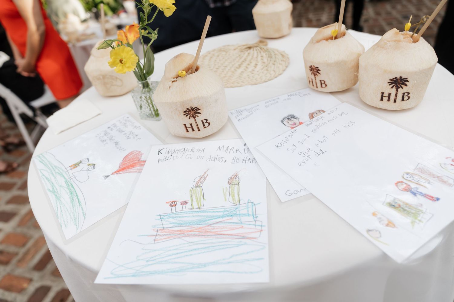 Children's drawings and artwork displayed on a white table with ceramic mugs and paper materials.