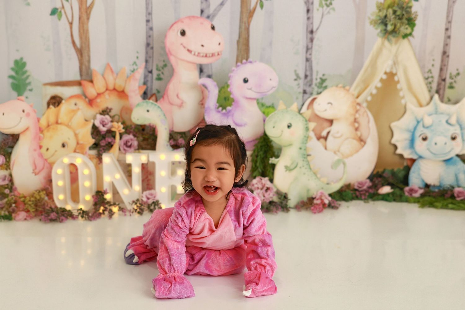 A baby in pink pajamas crawls across a floor decorated with Easter bunny decor and plush toys.