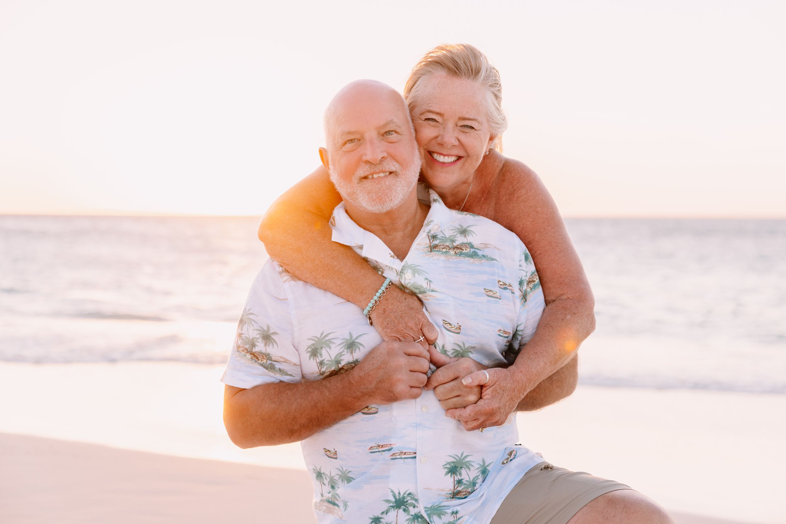 Happy couple sharing intimate moments on a sunlit beach.