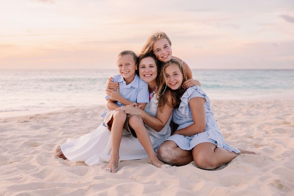 Family laying together on sandy beach during golden hour sunset.