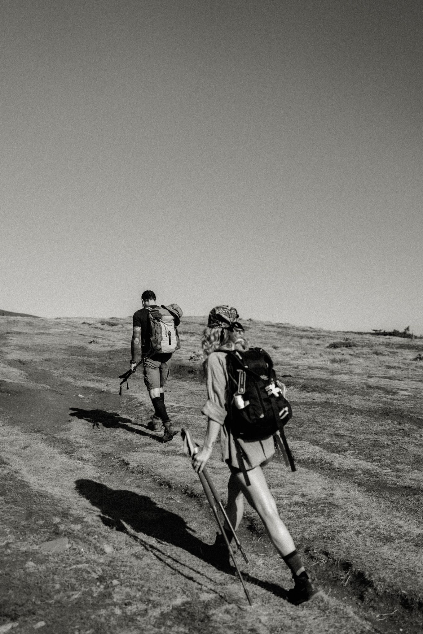 Three black and white photos show hikers traversing rugged terrain with backpacks and hiking poles.