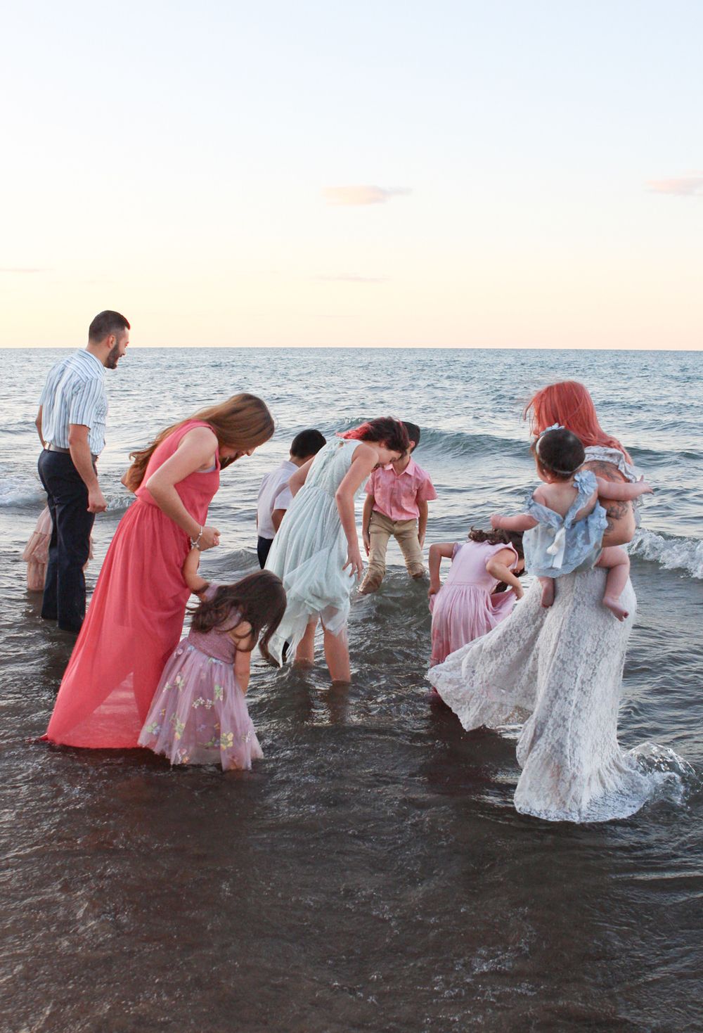 Group splashing and playing in ocean waves during golden hour.