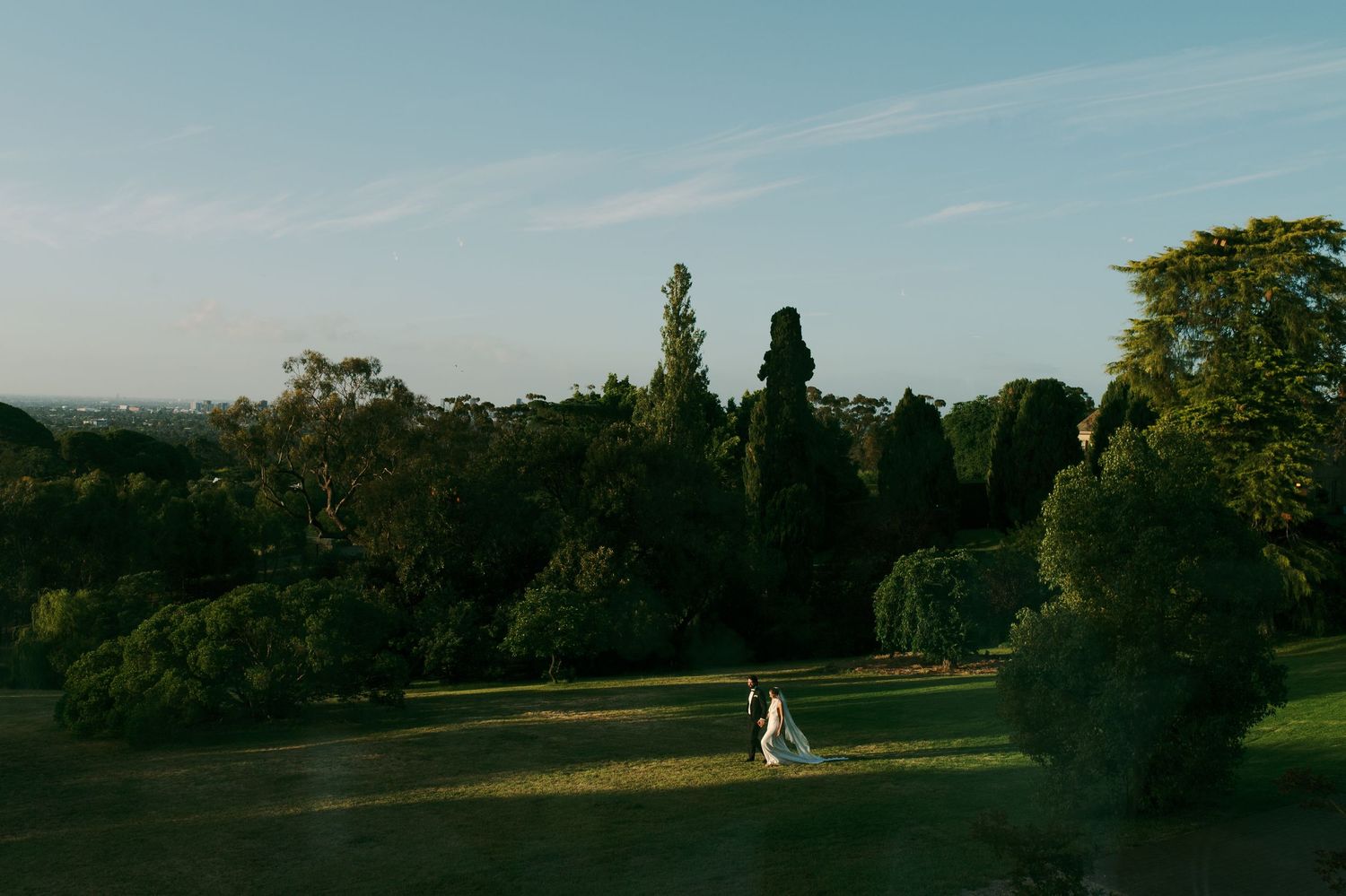 Romantic couple embraces in golden sunlit field at sunset creating silhouette against warm evening sky.
