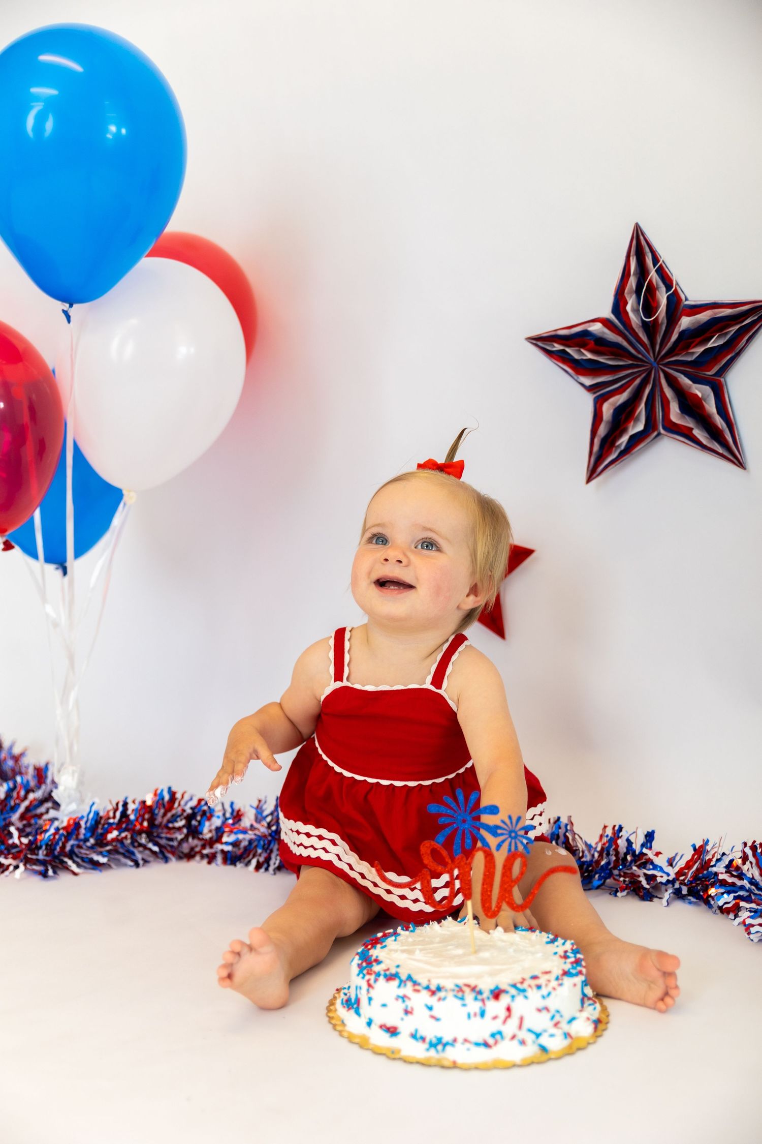 Four sequential photos show a baby in a red outfit celebrating their first birthday with a cake and patriotic decorations.
