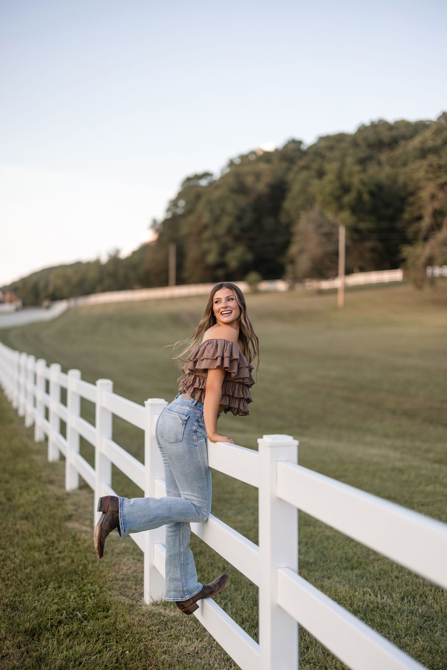 A series of three photos showing someone in casual denim sitting along a white wooden fence on grassy farmland.