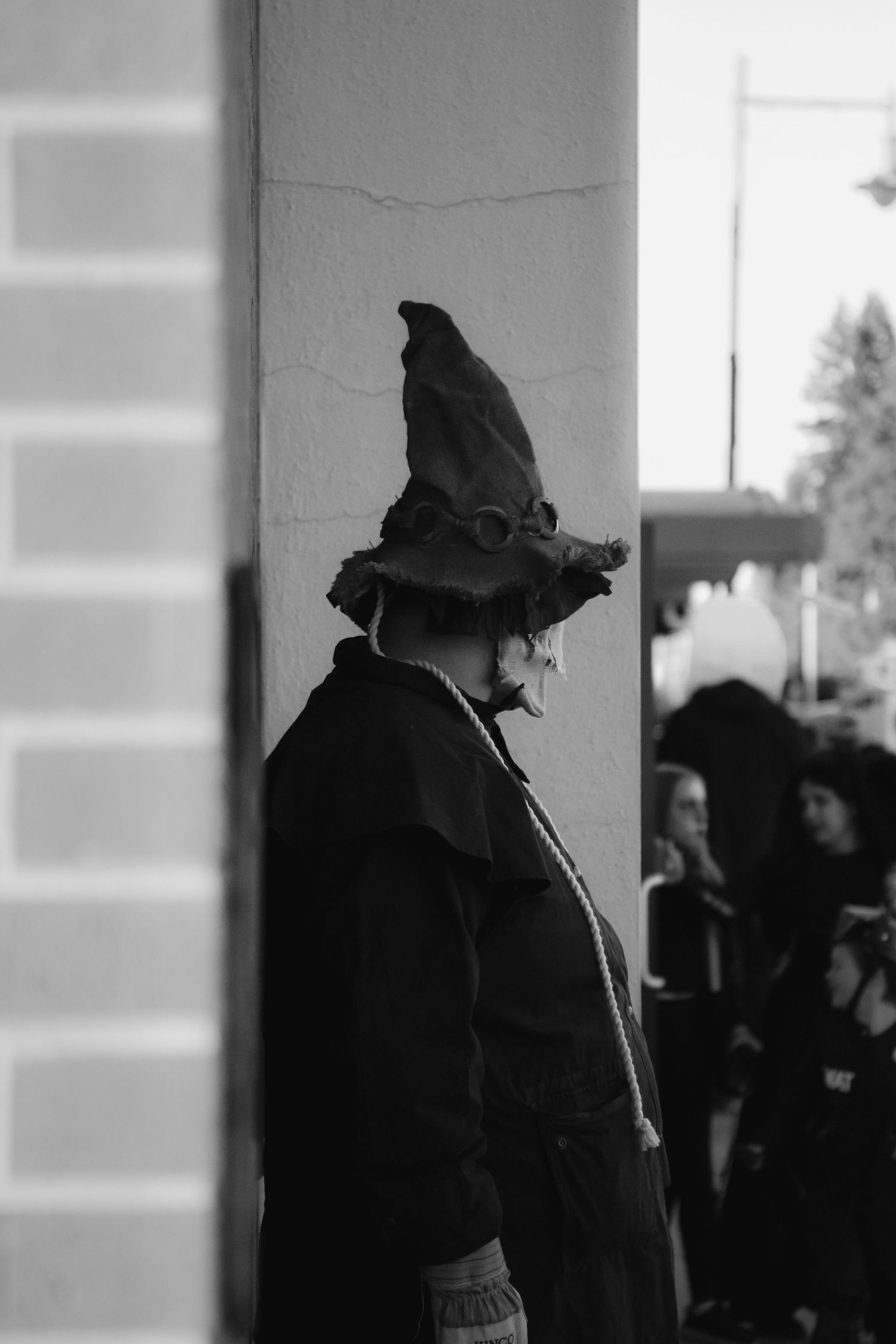 A person wearing a classic witch hat and costume in black and white.