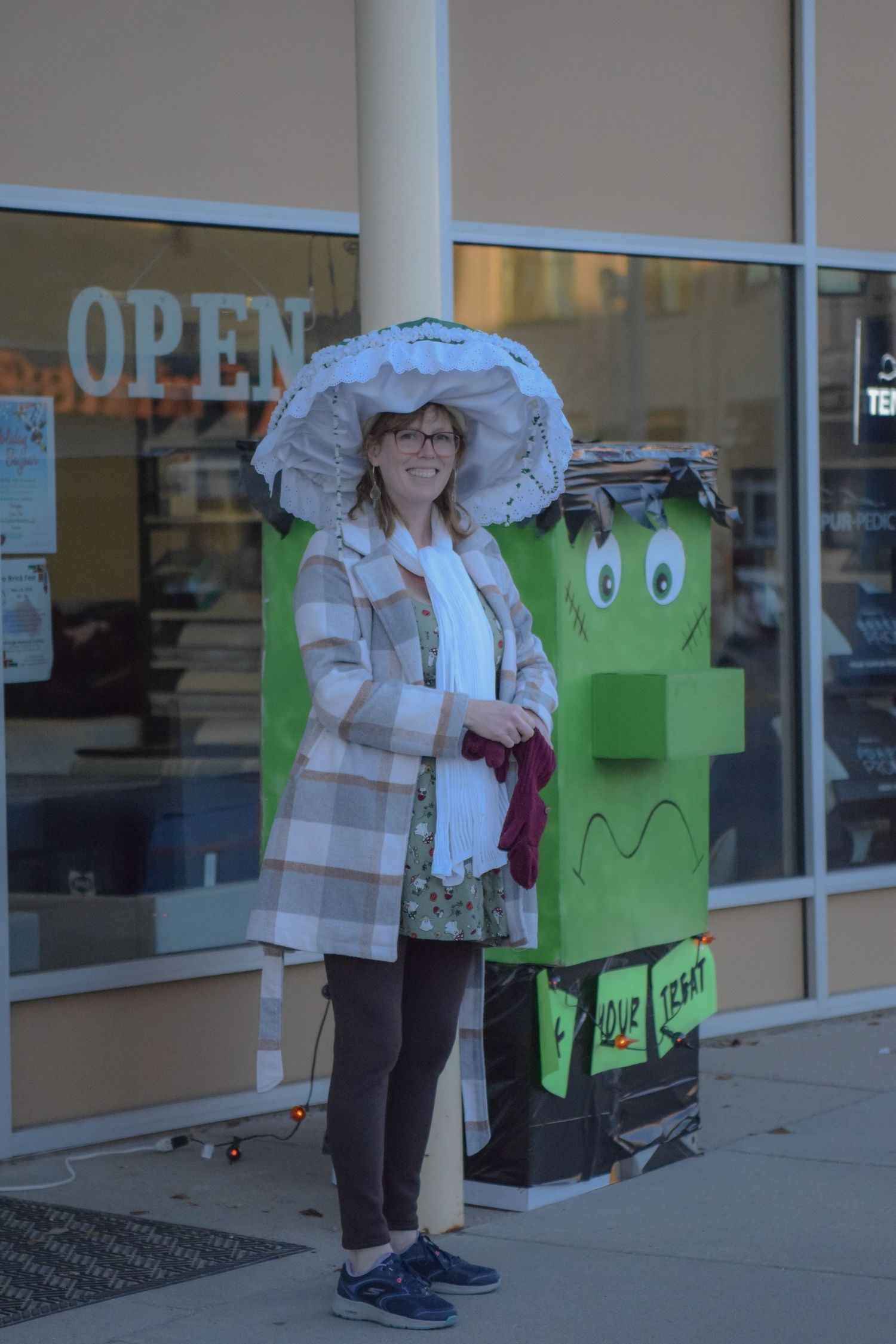 A green donation box stands outside a storefront window with reflections.