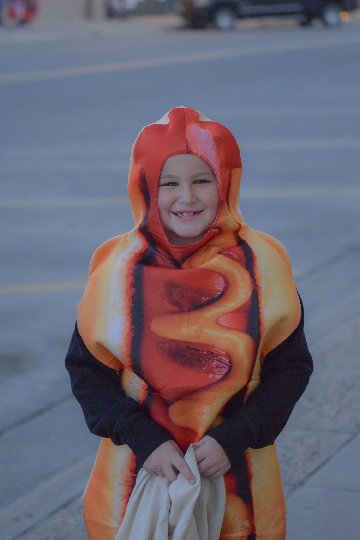 A person wearing an orange and black costume poses outdoors.