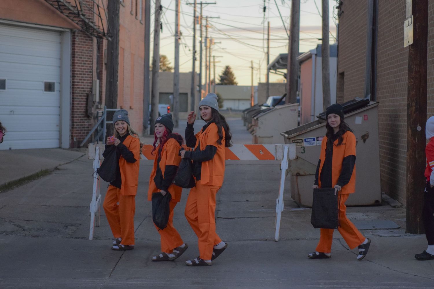 People in bright orange costumes walk down an alley during a Halloween event.
