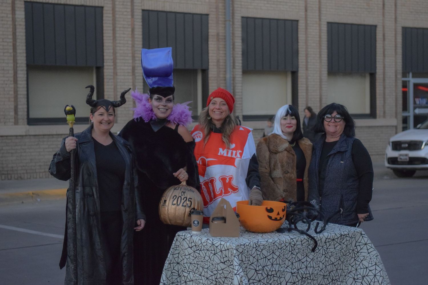 A group gathers outside a brick building during a Halloween trick-or-treat event.