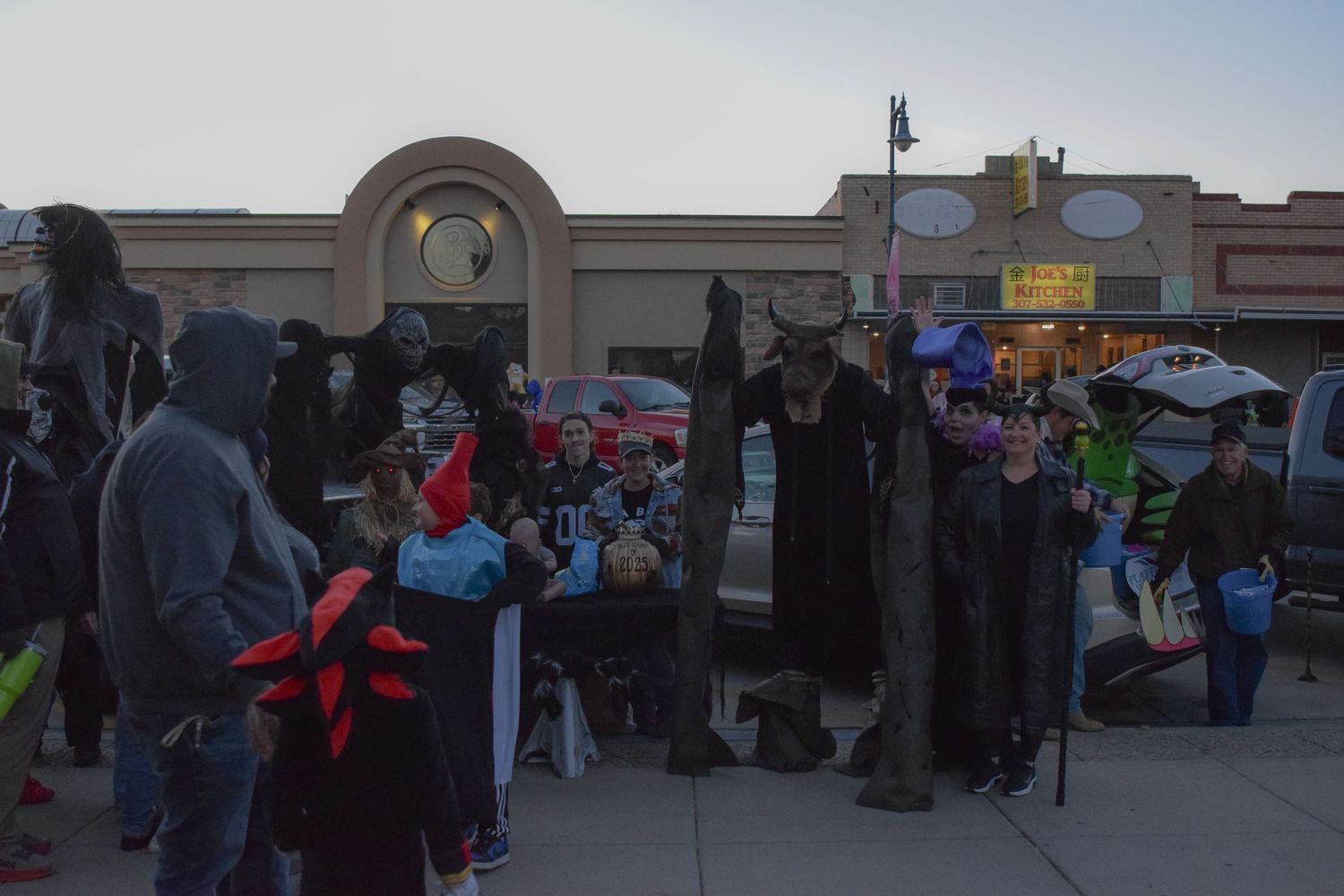 Crowd of people gathered outside storefronts during an evening community event.