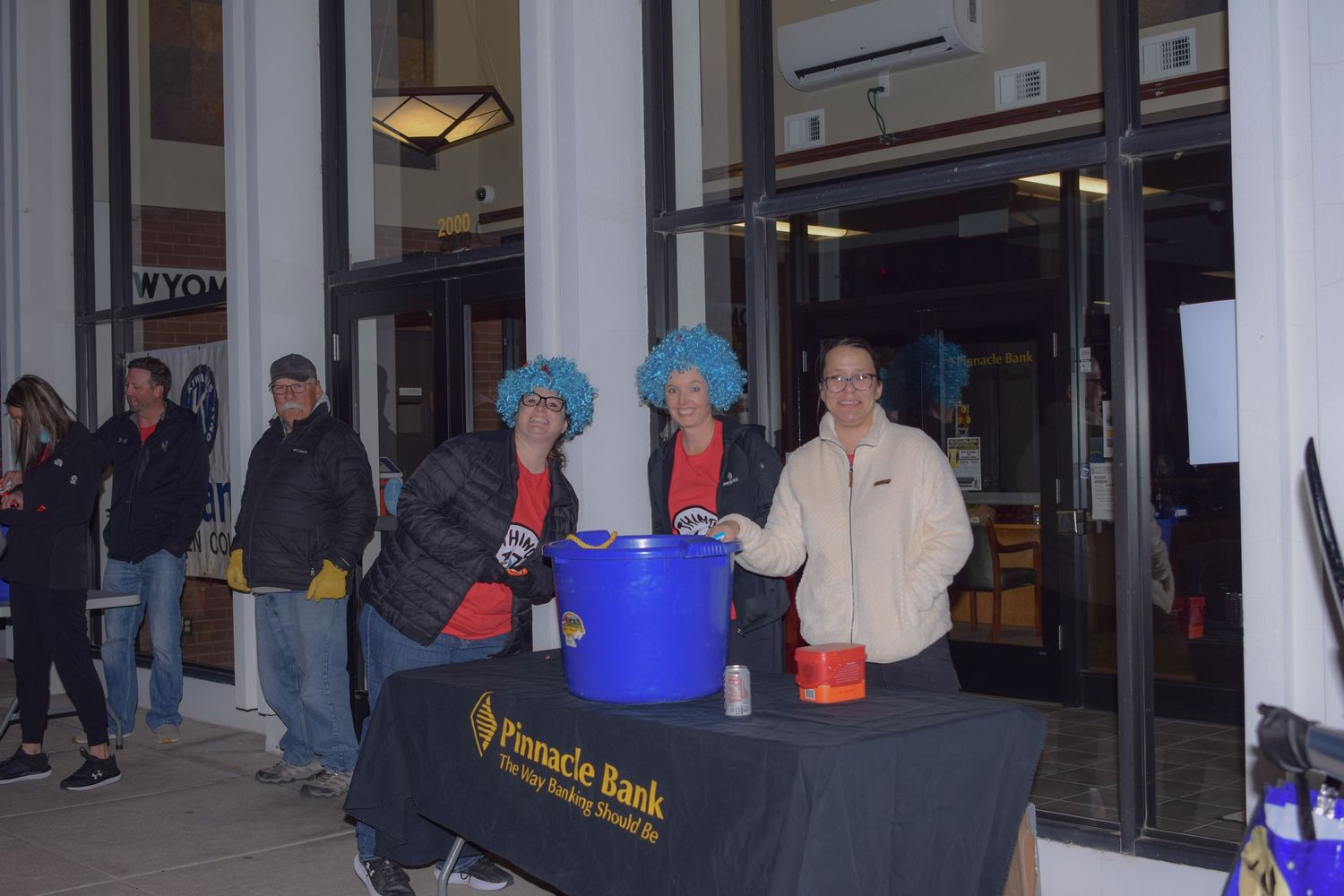 People lined up outside a storefront entrance during an evening event.