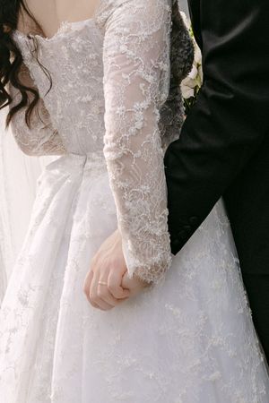 Close-up details of a bride's lace wedding dress sleeve and bodice.