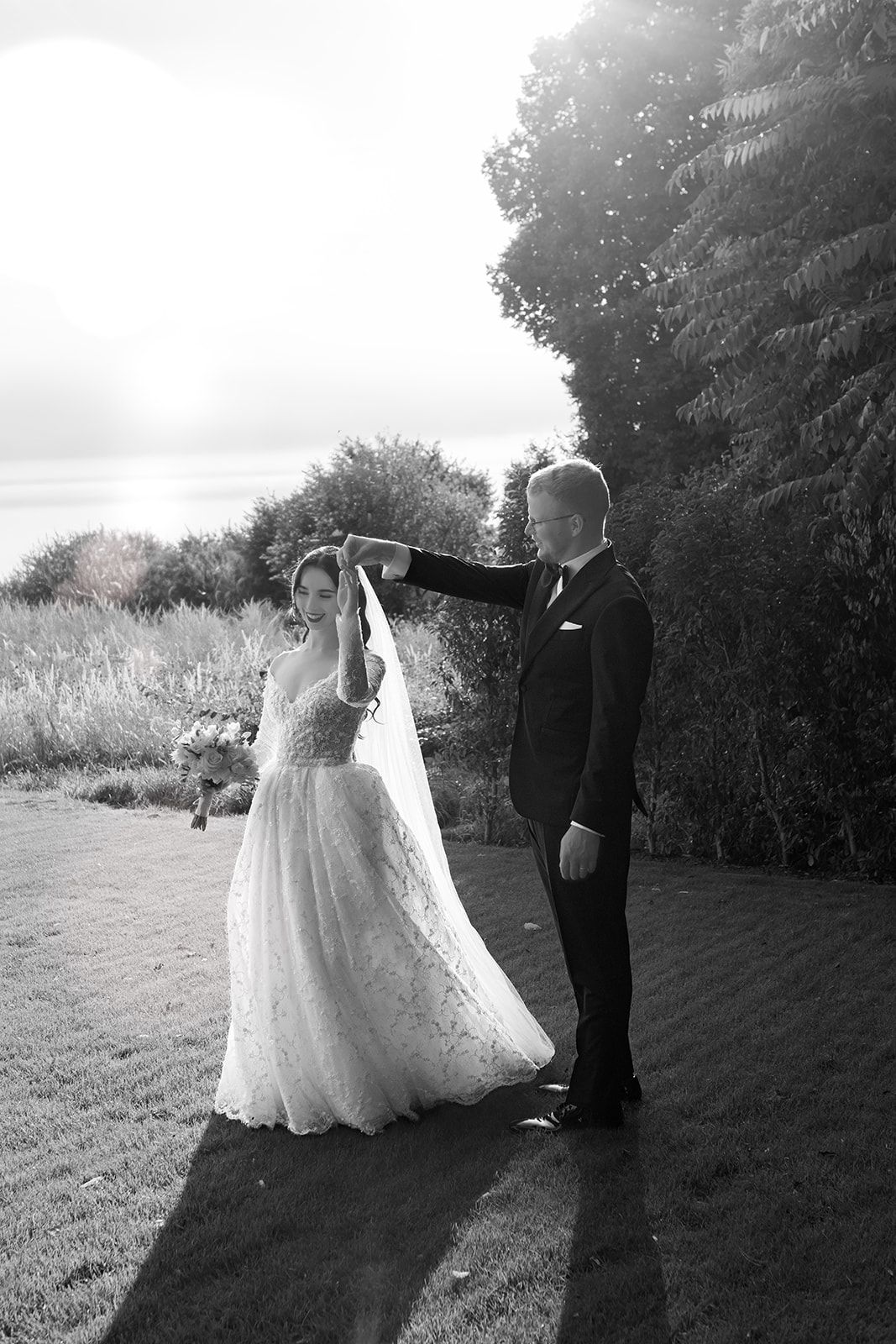 Wedding couple sharing intimate moments in a sunlit outdoor garden setting.