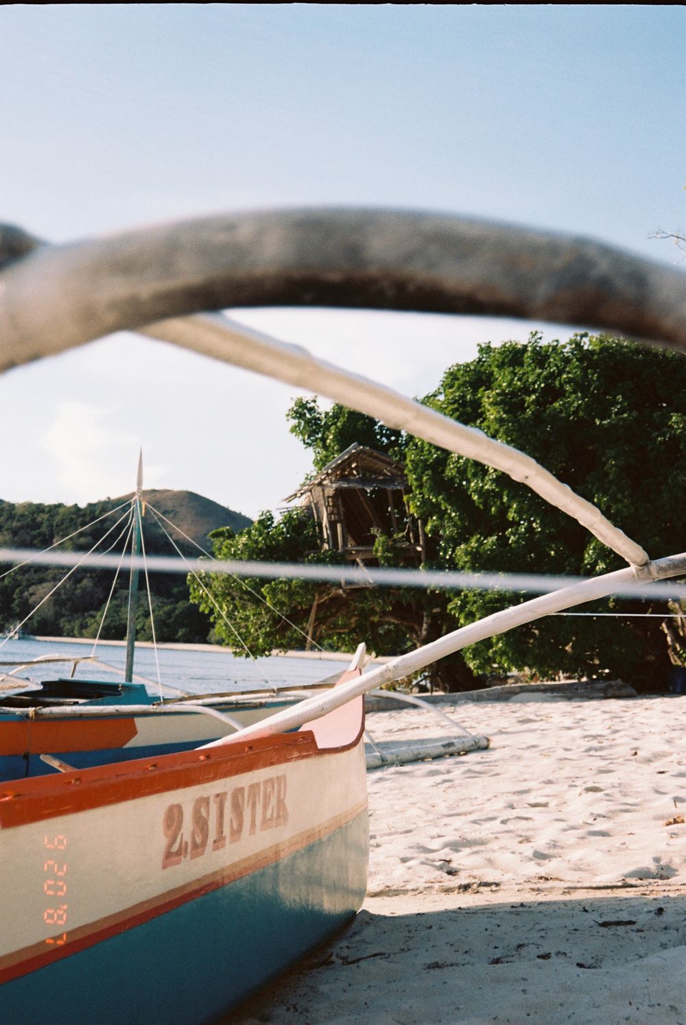 Traditional wooden outrigger boat resting on a pristine white sand beach.