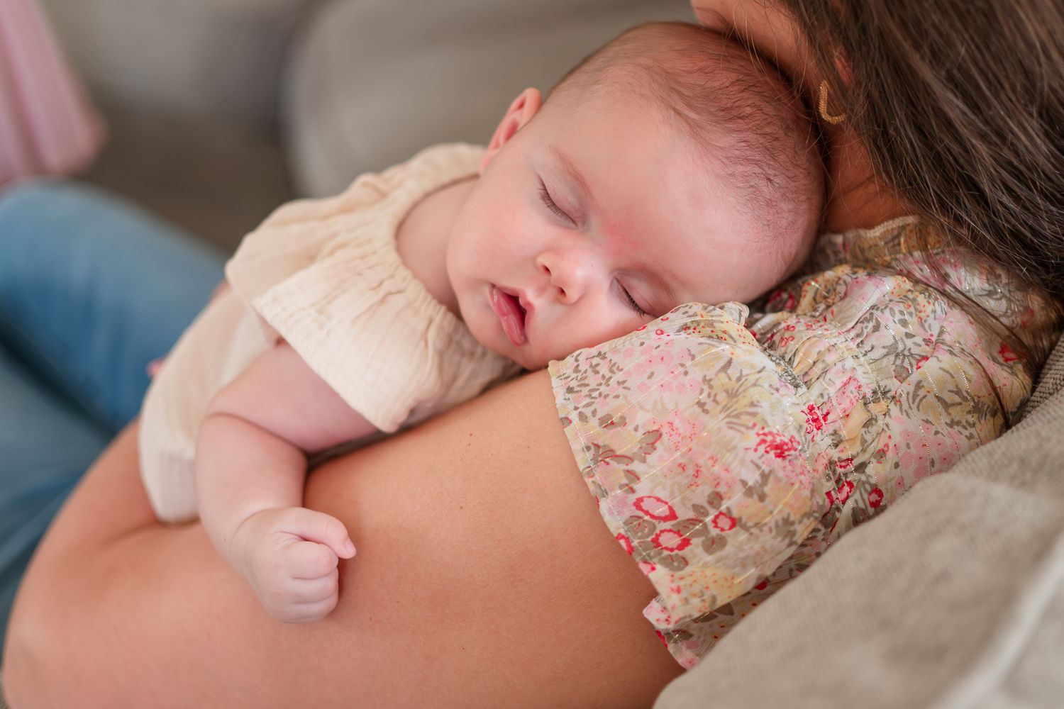 Newborn baby sleeping peacefully on floral bedding in soft natural light.