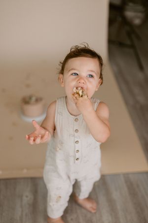 A baby in a white romper plays on a gray wooden floor in a series of candid shots.