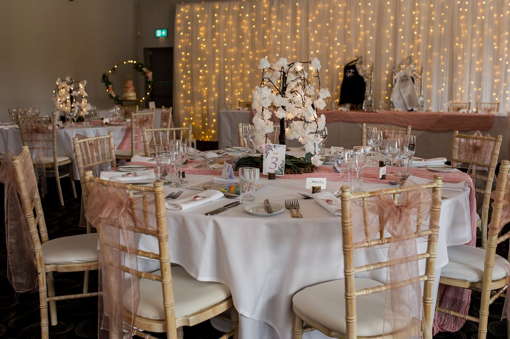 Wedding reception venue decorated with romantic fairy light curtains and round tables.