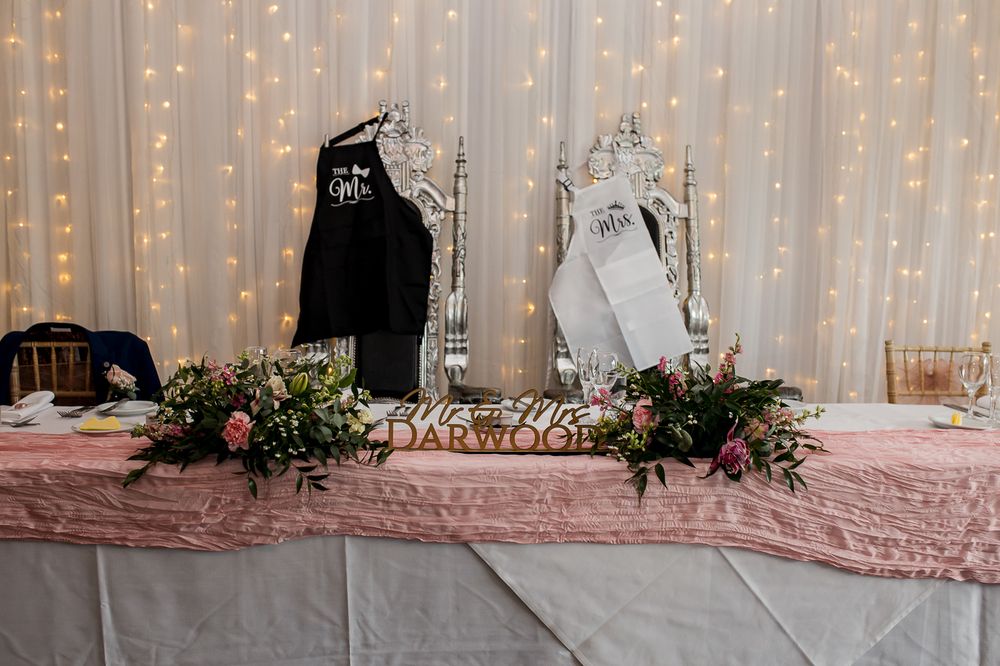 Reception venue with fairy light backdrop and elegant table settings in soft pink tones.