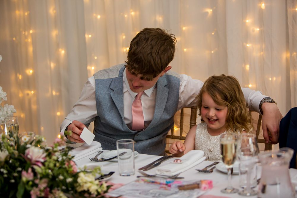 Guests enjoying a wedding reception dinner under warm string lights and elegant decor.