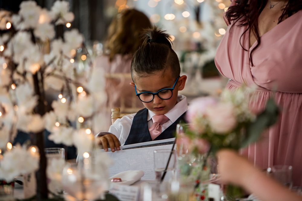 Wedding reception table settings with pink accents and fairy light backdrop.