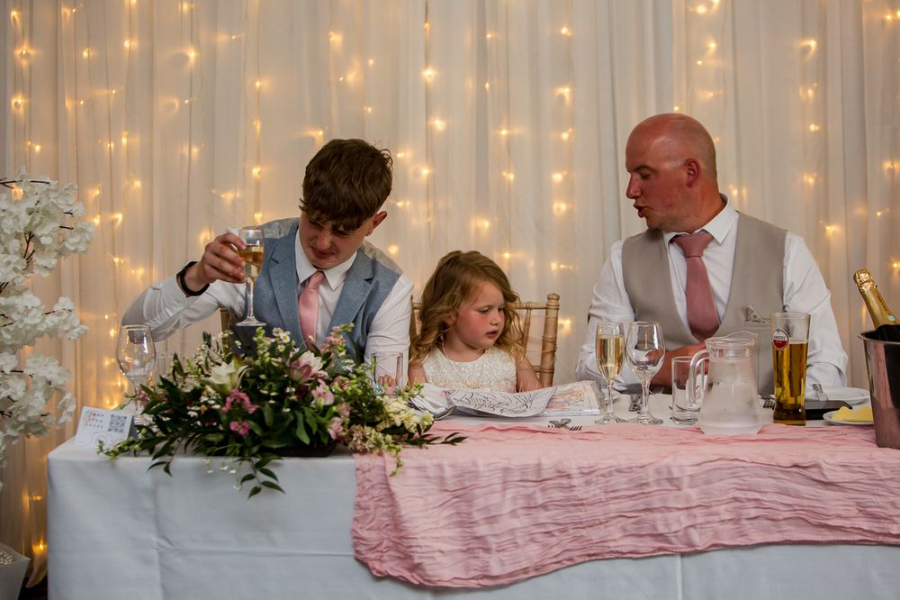 Wedding reception hall decorated with string lights and floral centerpieces.