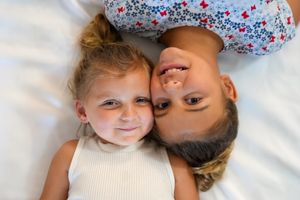 Parent and child lying on white bedding share tender moments in a series of connected photos.
