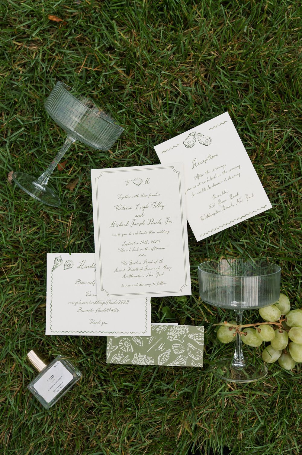Wedding invitations and stationery laid out on grass with elegant floral designs.