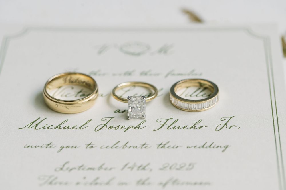 Wedding invitation details and rings displayed on elegant white paper.