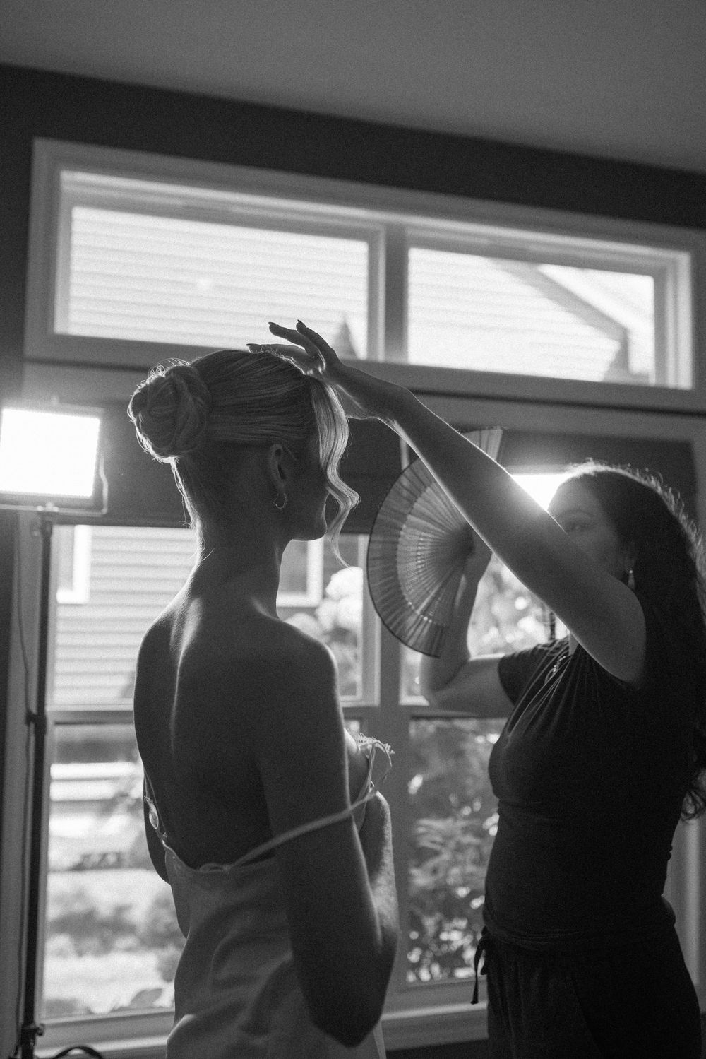 Silhouettes of people getting ready against bright window light.
