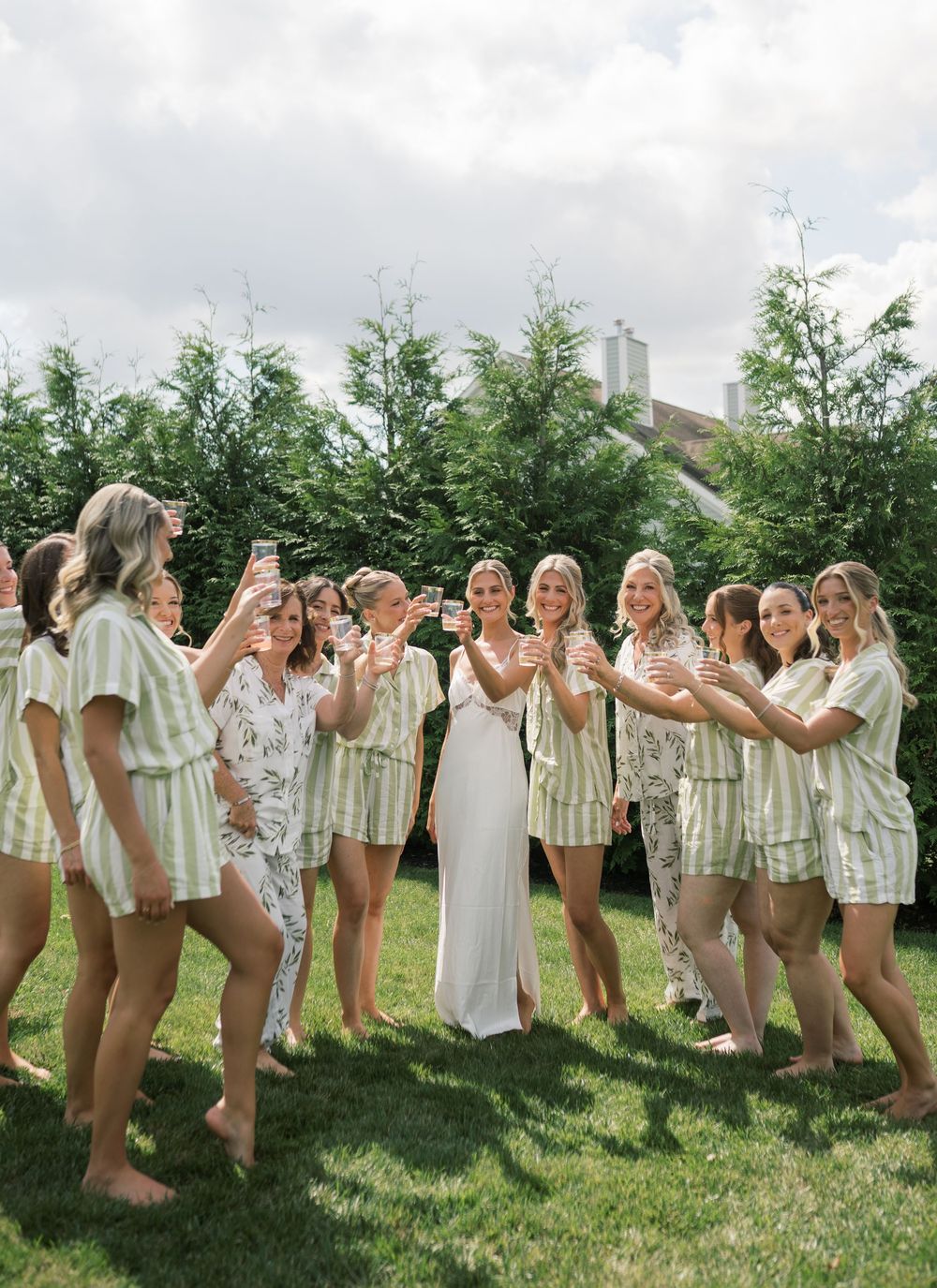 Wedding party in matching outfits posing together on green lawn.
