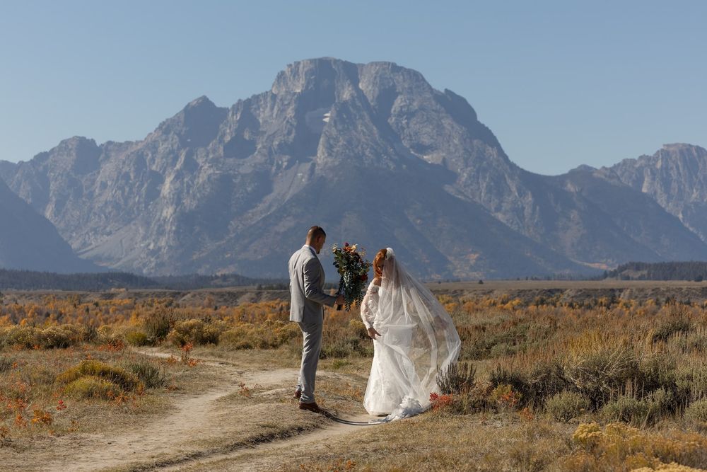 A wedding ceremony unfolds on a scenic mountain trail with the dramatic Teton Range peaks in the distance.