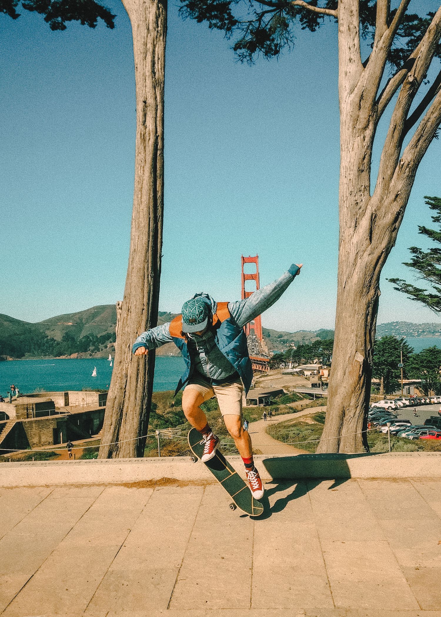 Sequence of a skateboarder performing a trick near trees with the Golden Gate Bridge visible in the background.