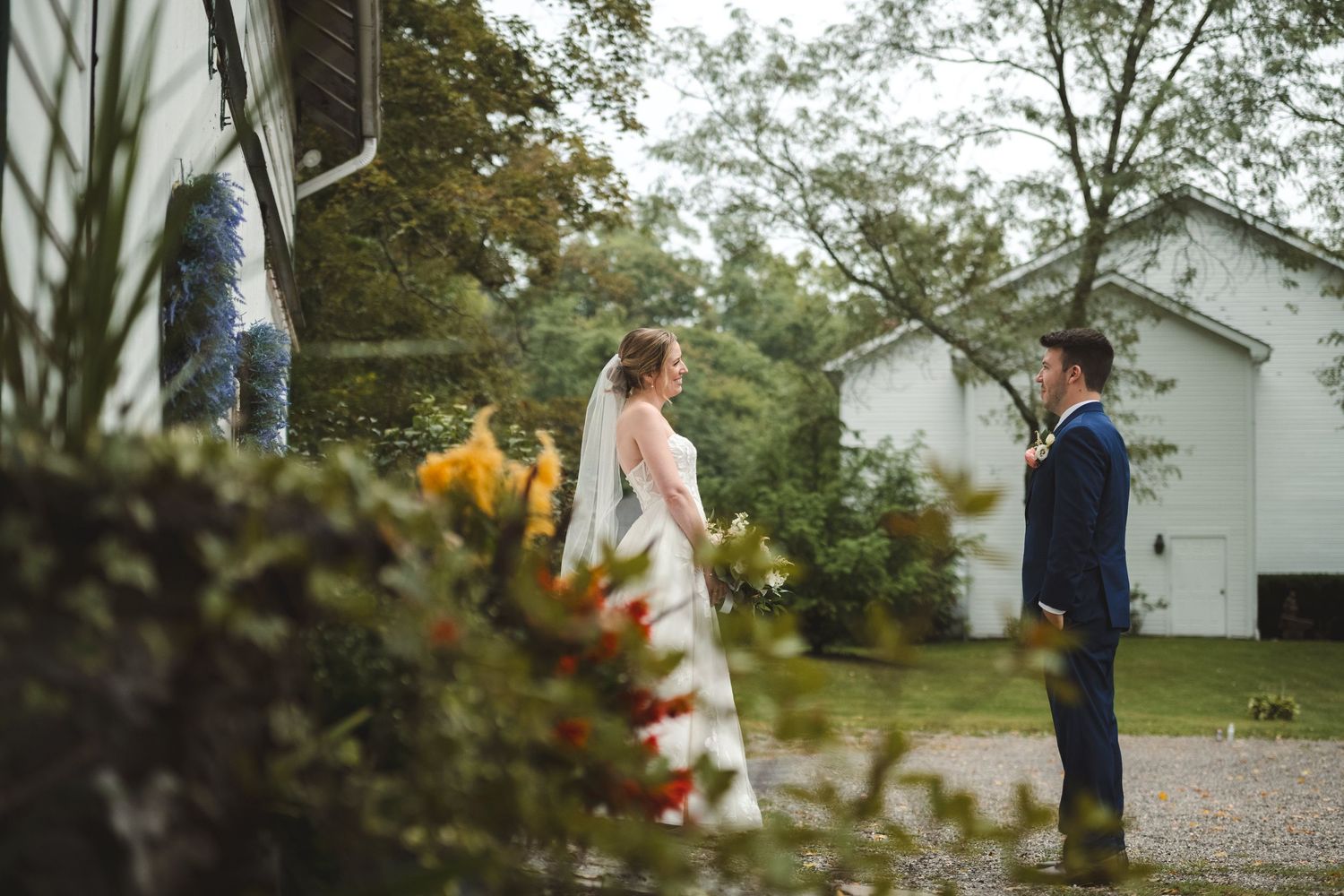A couple looking at each other surrounded by a white barn at The Curry Estate in Hopewell Junction.
