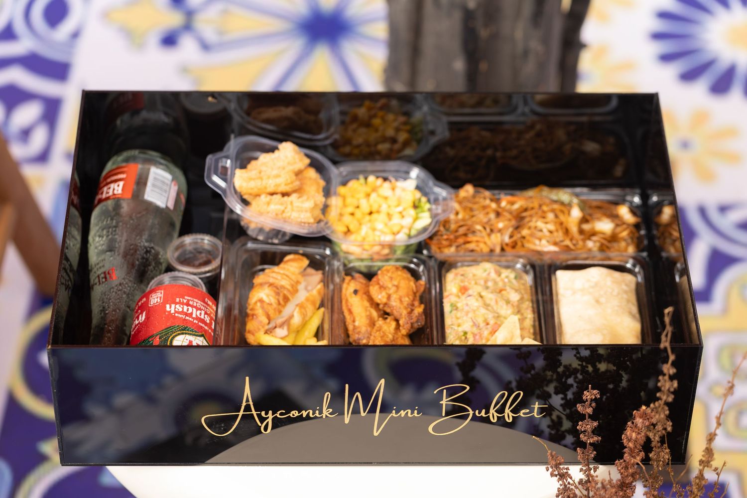 Black gift box containing assorted snacks and treats with gold lettering.