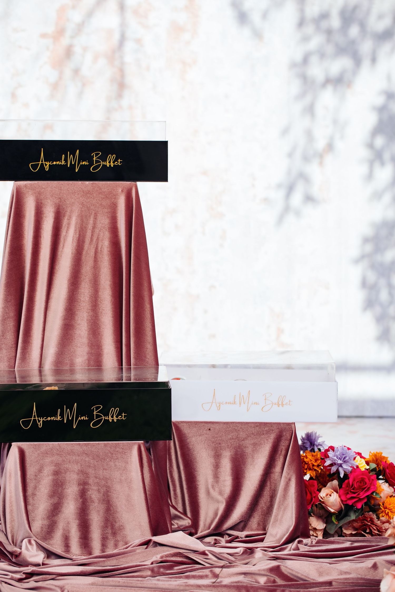 Minimalist product display with rose gold fabric and black branded signage.