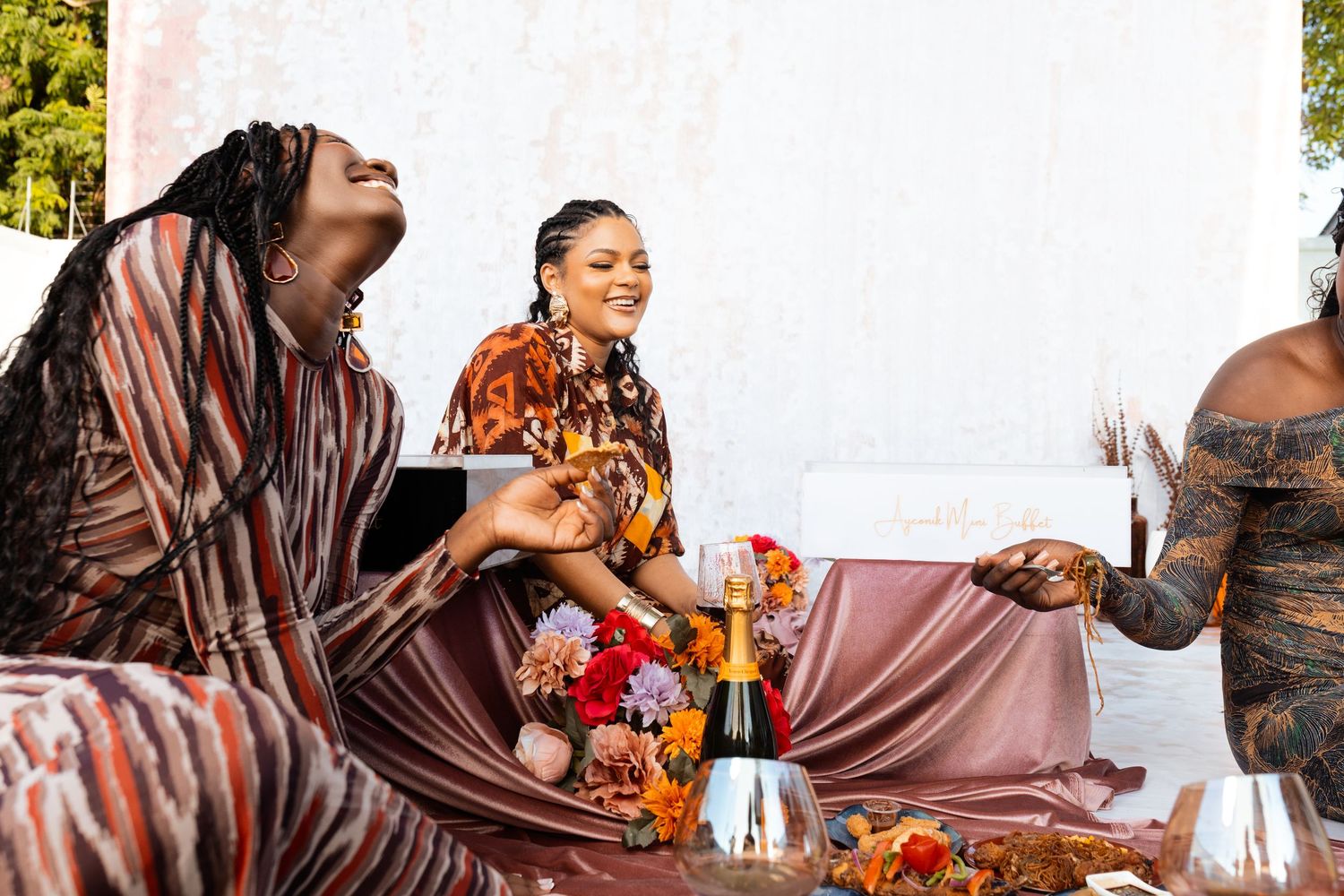 A festive outdoor picnic gathering with people enjoying drinks and conversation.