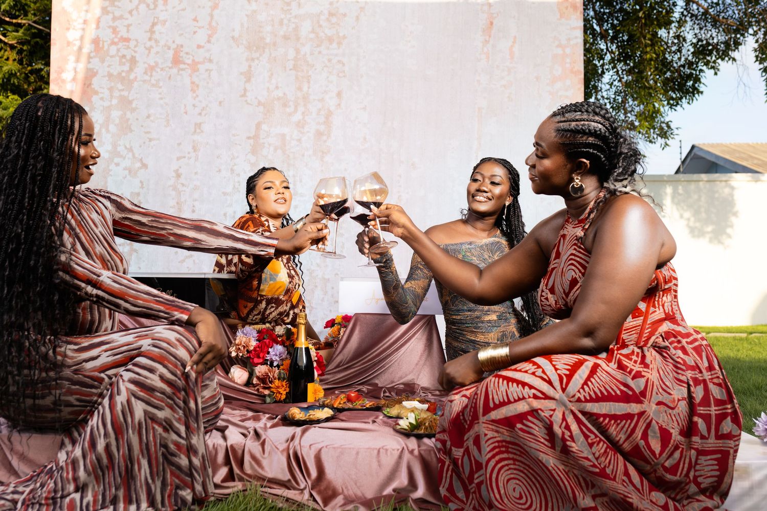Friends toasting and celebrating at an outdoor picnic with drinks.