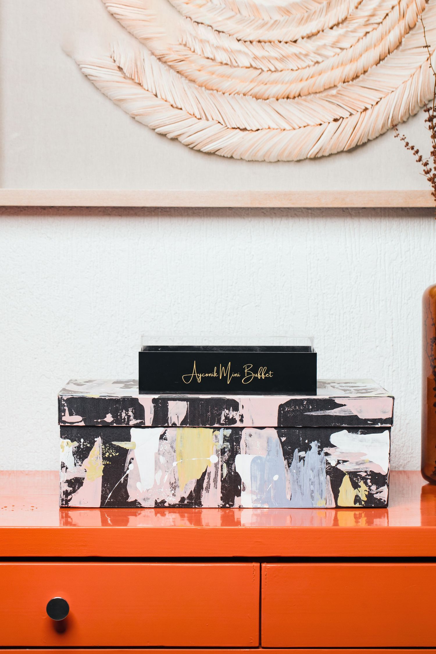 Modern display setup with orange shelf and black branded signage against textured background.