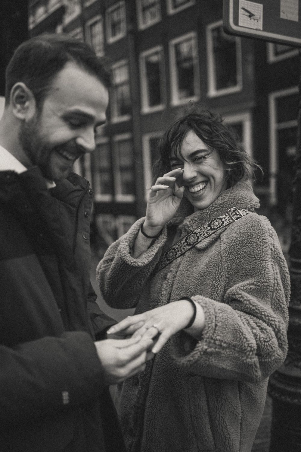 Black and white candid moment of a couple laughing together on an urban street.