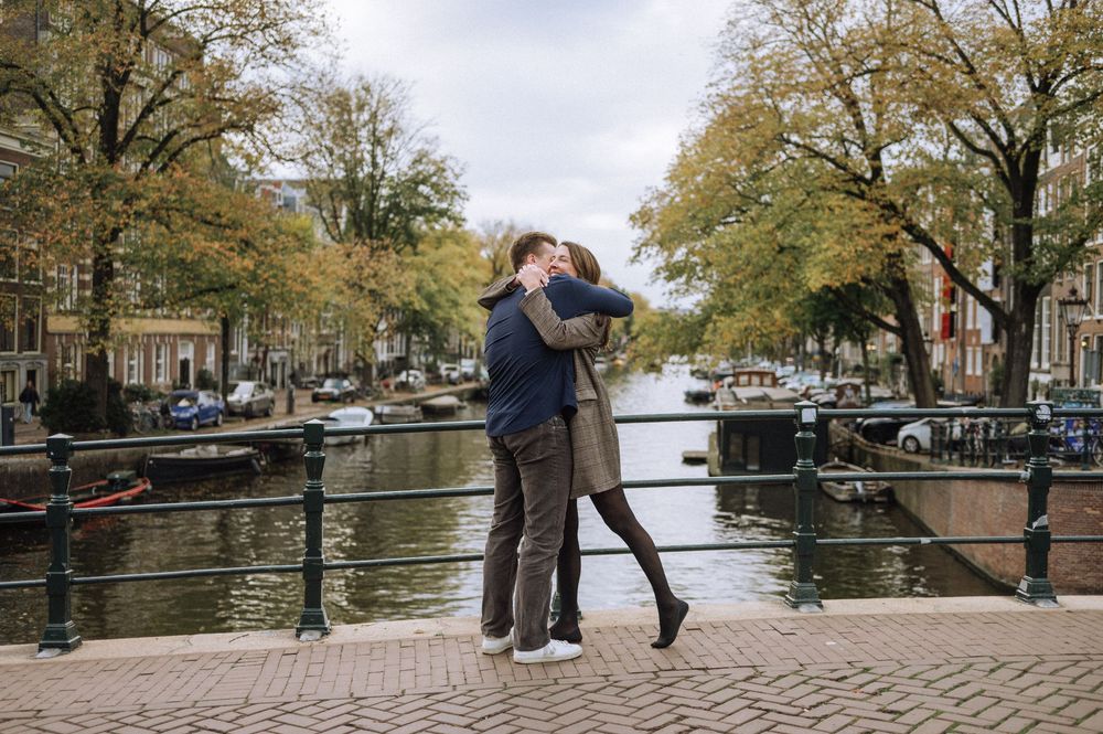 A couple sharing an intimate moment on a bridge overlooking Amsterdam canals.