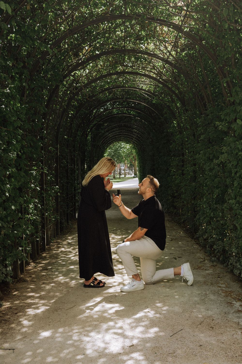 Couple reading books together under a leafy garden archway.