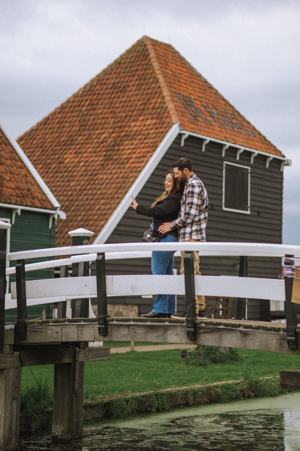 Traditional Dutch houses with orange tiled roofs beside a wooden bridge over water.
