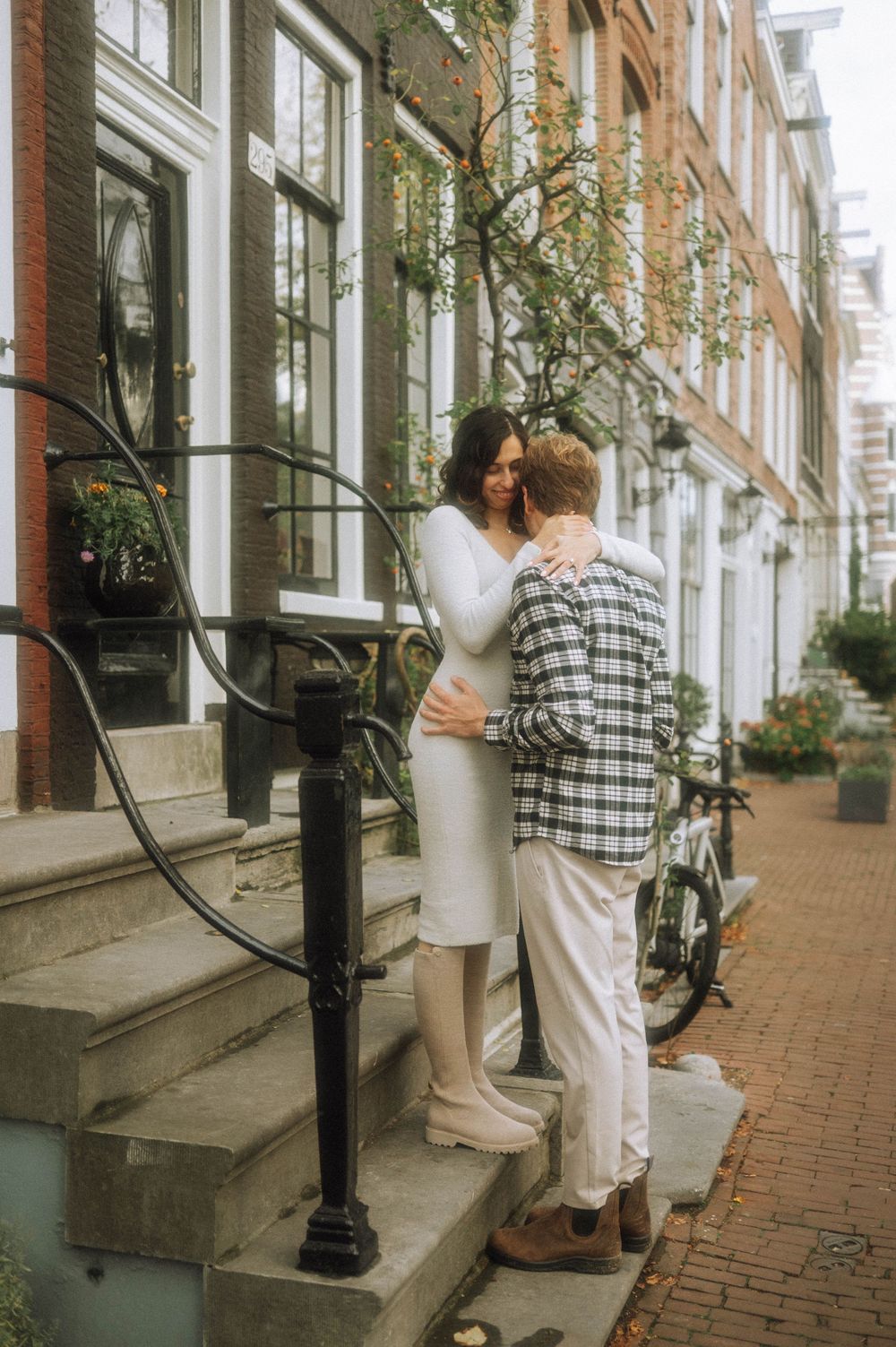 Couple sharing a tender moment on brick steps outside historic buildings.