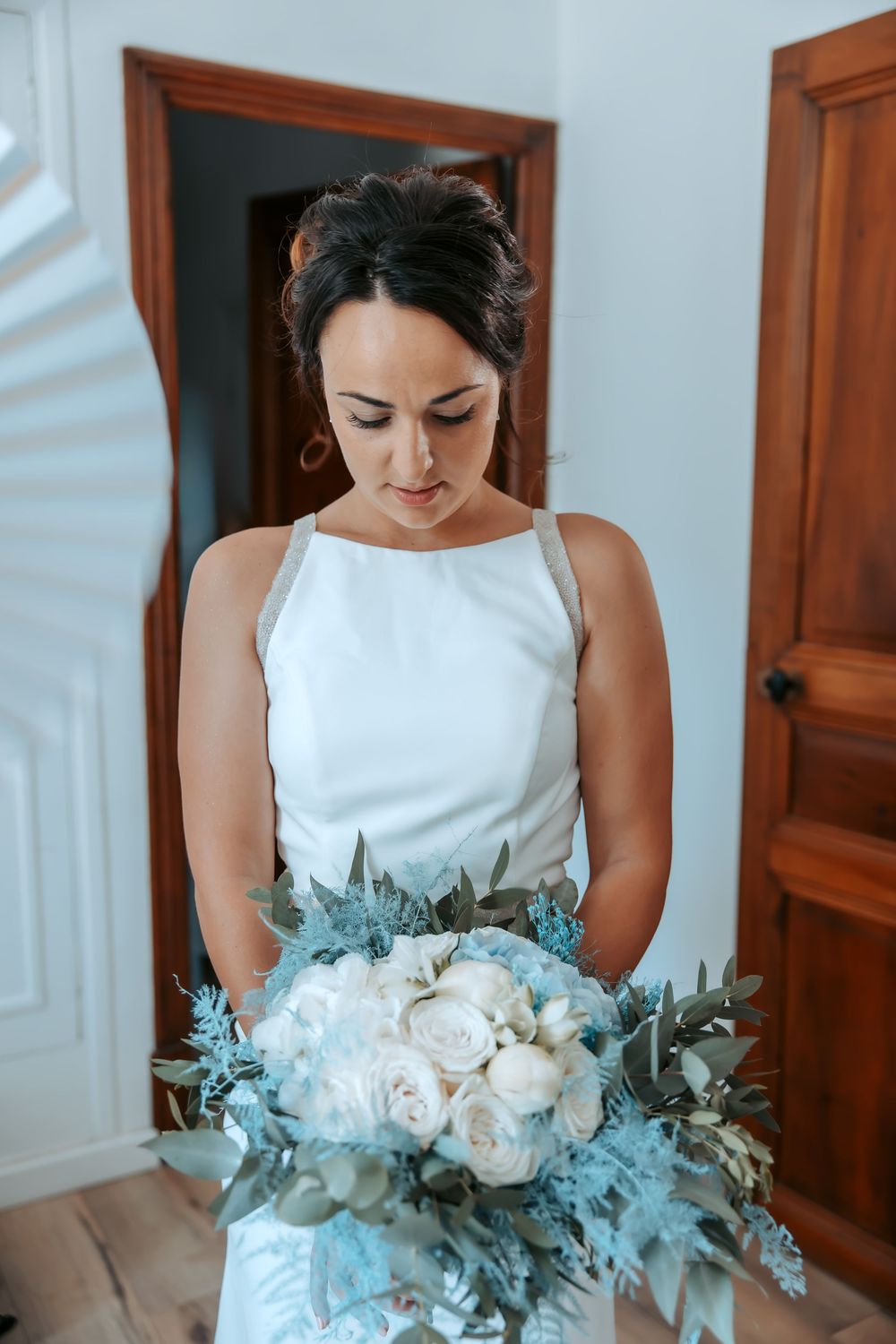 Beautiful white bridal bouquet with roses and eucalyptus leaves against a wooden door background.