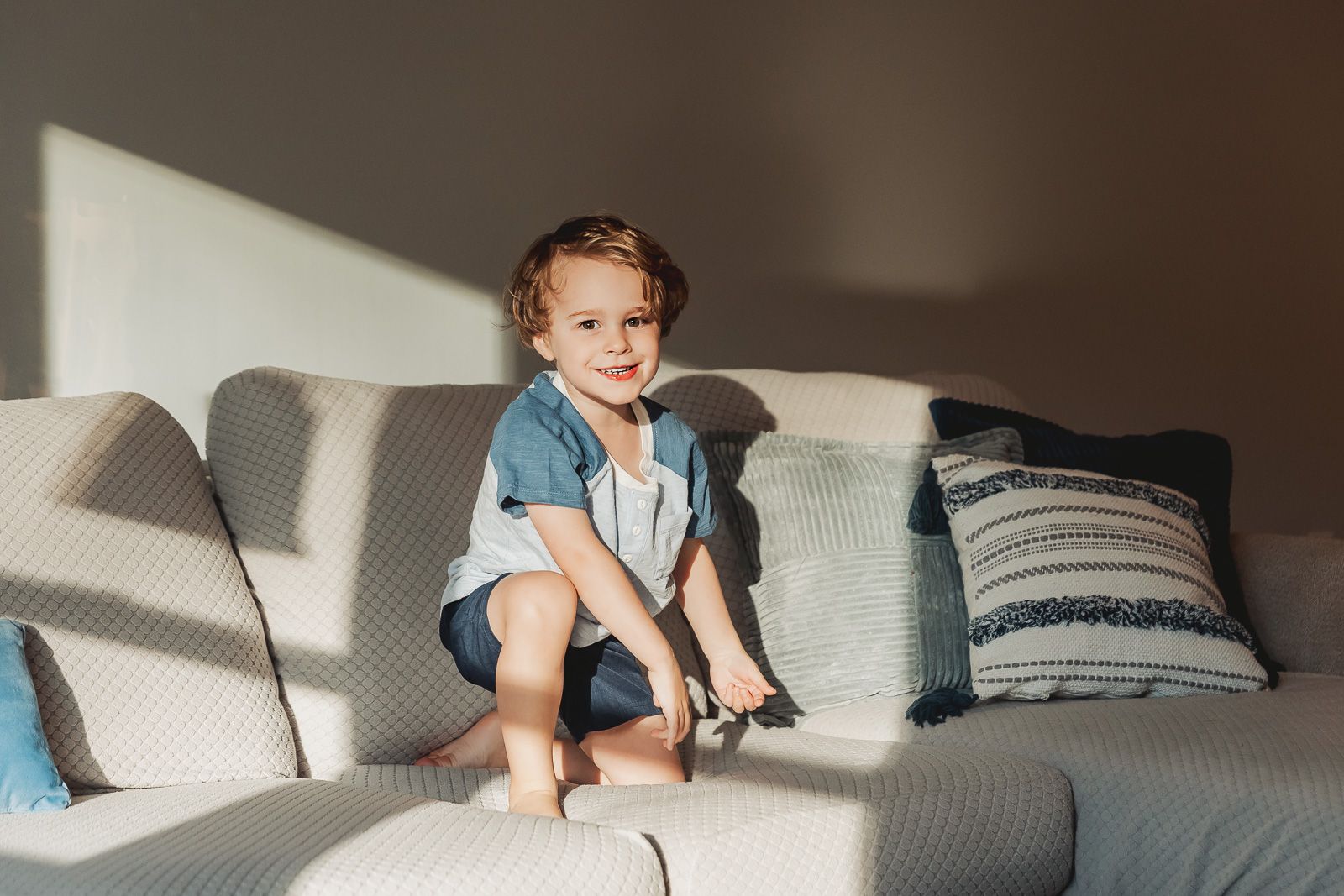A child sits comfortably on a gray couch while using a digital tablet device.