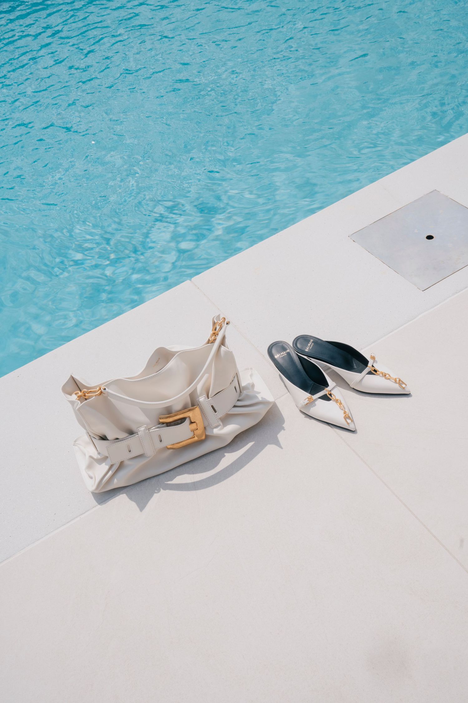 A pair of elegant beige ballet flats arranged artistically by a turquoise swimming pool.